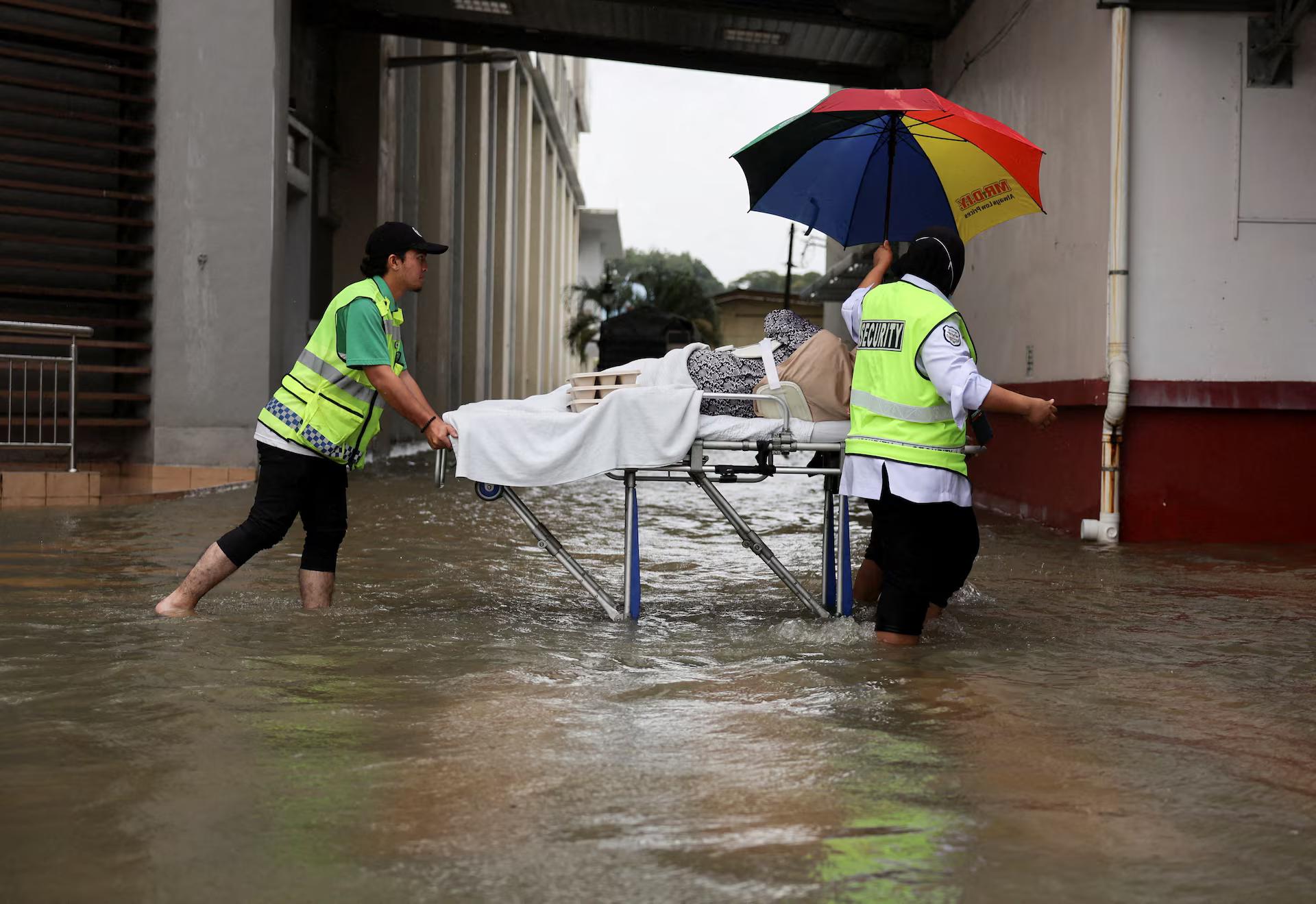 Hospital staff push a patient on a stretcher through floodwater.