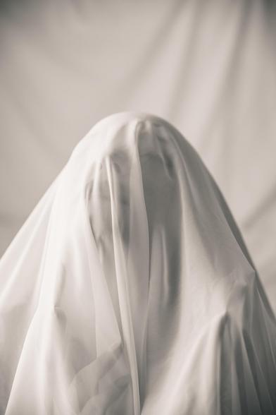 Mujer bajo tela blanca.