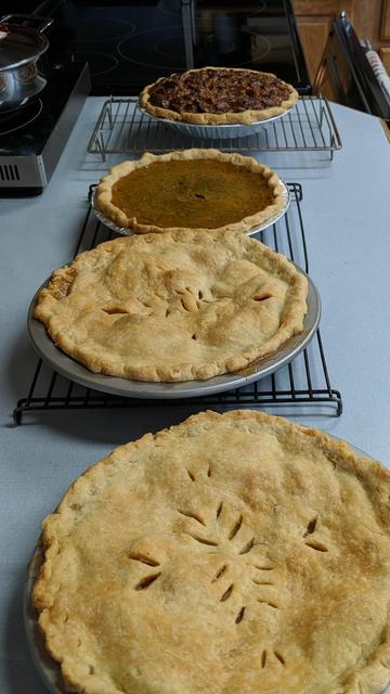 4 pies. At the top is a pecan pie, next a pumpkin pie, and the two closed are apple pies. The crust was made with:
5 cups of flour
2 cups of butter
1.5 teaspoons salt
those things mixed in the food processor
1/2 cup of water
1 beaten egg
1.5 teaspoons apple cider vinegar
those things mixed into the buttery flour
divide and make balls and proceed to make crust or wait.
They were divided into three 450 gram balls. and two were divided 250/200 for double crusts and in half for the single crusts in smaller pans. It could probably stand to have just a little more dough for 2 doubles and 2 singles so probably 6 cups of flour, 2.5 cups butter, and a little more water.


