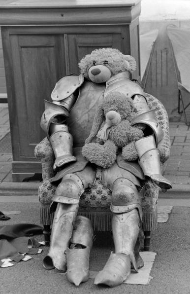 un nounours dans une armure, sur un trottoir, en noir et blanc