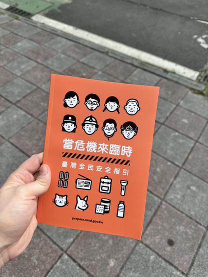 Orange booklet with white text 「當危機來臨時」 (In time of crisis)