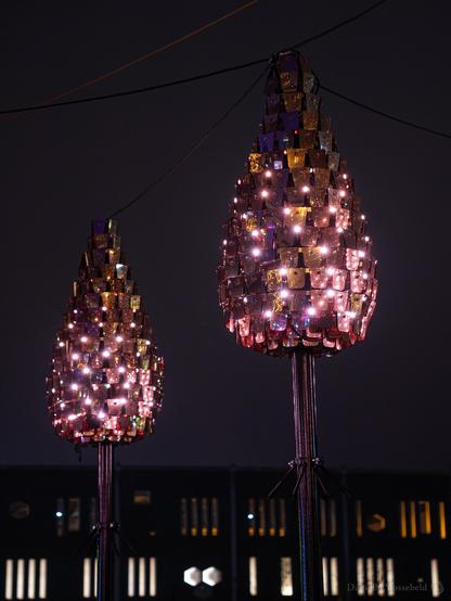 Two lamps, cone shaped with more lights in them. In the background The Bijenkorf shop. 