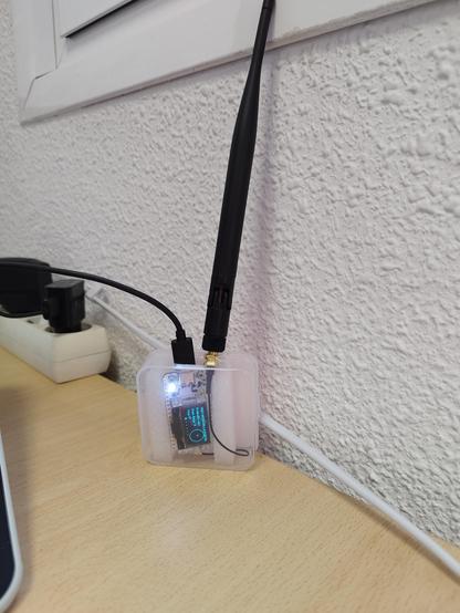 Another meshtastic device. It has an aspect of a board in a random plastic box (not designed for it) with a quite big antenna (compared with the board size) pointing upwards. The device is conected to power through a USB wire.