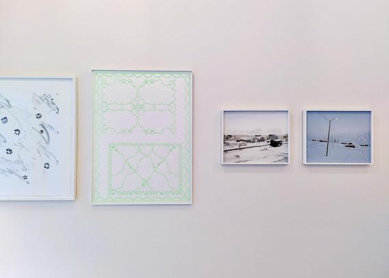 Vier ingelijste werken aan de muur. De twee grotere werken links zijn van Sofie Vandevoorde, de twee kleinere foto's rechts van Catherine Lemblé. Helemaal links een monotype met minimalistische, sierlijke lijnen en suggesties van bloemen in donkergrijs op een witte achtergrond, daarnaast een zeefdruk met fluogroene kleine bloemen die een patroon vormen. De twee rechtste werken zijn foto's van een sneeuwlandschap in Spitsbergen, waarop van op afstand oa. huizen te zien zijn. 