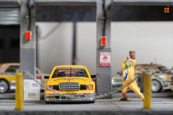 A Mercedes Benz 190E 2.5-1.6 Evolution II, Camel 1990 Yellow Page livery by LMLF in 1:64 scale with 1:64 figure on AREA 164.