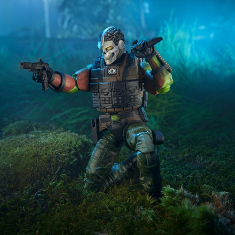 the figure seen from the front in a three quarter view, holding and aiming a pistol, he has a skull mask with gold eyes and exposed brain for the dome of the skull 