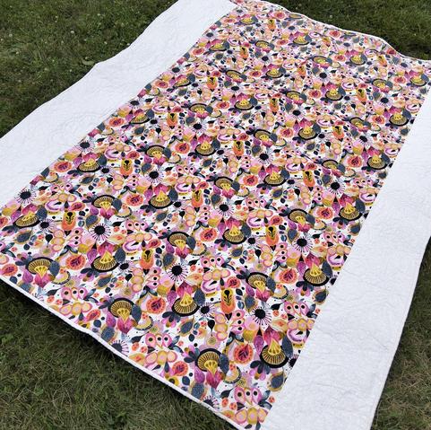 the reverse side of the quilt, it is a  swirling multi-colored pattern in reds and golds with white borders running up the sides 