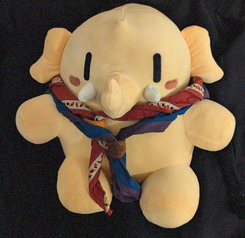 Das Mastodon trägt zwei Pfadfinder*innenhalstücher: das blaue mit violettem Streifen vom VCP und das rote mit grauem Streifen vom rdp.