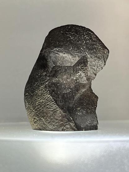 Photo of a small black lump of indifferent shape but with small lines of a fingerprint.