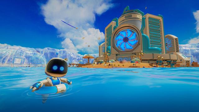 A wallpaper/screenshot of a scene from the game - our protagonist Astro (a cute and chibi style robot) floats in the blue waters with an inner tube around its waist off a beach island in the foreground. The island behind us has a golden sandy beach with golden palm trees where other small robots frolick with beach balls, and relax under beach umbrellas. We can also see there is a short pier. Further in the background crossing the length of the scene we see a wall of ice. The focal point of the island is a large complex that represents a part of a computer - it is crisscrossed with large tubes, and above its entrance is a huge fan dominating the facade of the building. The weather is bright and sunny with a deep blue sky and just a bit of clouds.