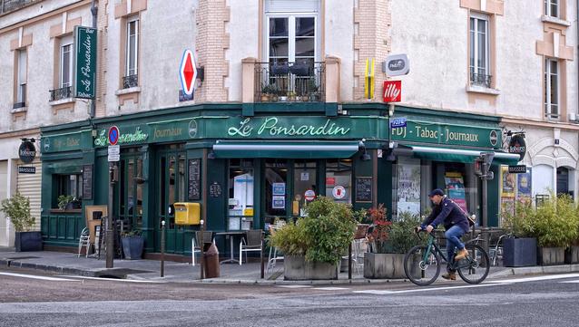 Le Ponsardin tabac shop in Reims, France, with a bicyclist on the street in front