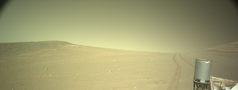 Image captured on the slopes of the rim of Jezero Crater, with the Mars rover Perseverance's UHF antenna in the foreground to the right, with rover tracks receding away in the distance.
