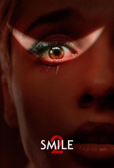 The film poster for Smile 2, showing a woman's face under blood red lighting, with a smile shaped crescent across her right eye