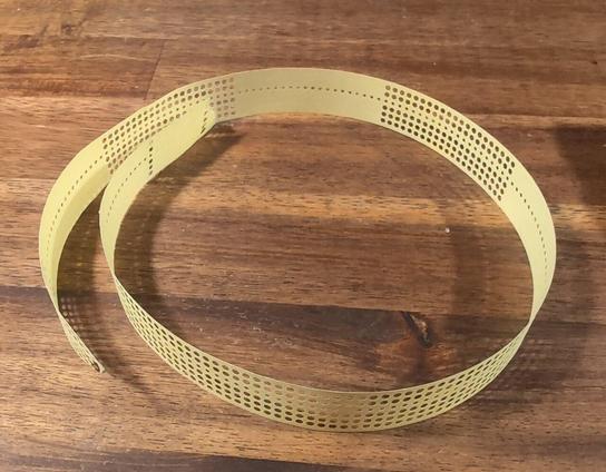 A short piece of 5-channel paper tape sitting on a desk. It has one block of all-ones and a few alternating blocks of 21 all-ones and all-zeroes punched.