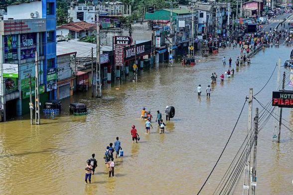 Des gens traversent une rue inondée après de fortes pluies à Wellampitiya, en périphérie de Colombo, le 30 novembre 2025. Les autorités sri-lankaises ont lutté contre la montée des eaux dans certaines parties de la capitale le 30 novembre après qu'un puissant cyclone a laissé une traînée de destruction, tuant au moins 159 personnes à travers le pays.