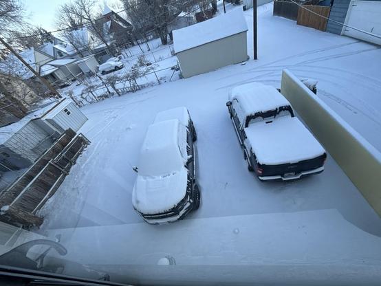 View from my 2nd floor back apartment window looking down at 2 pickups buried in deep snow. The area around it is not plowed nor is the alley the parking area opens onto.