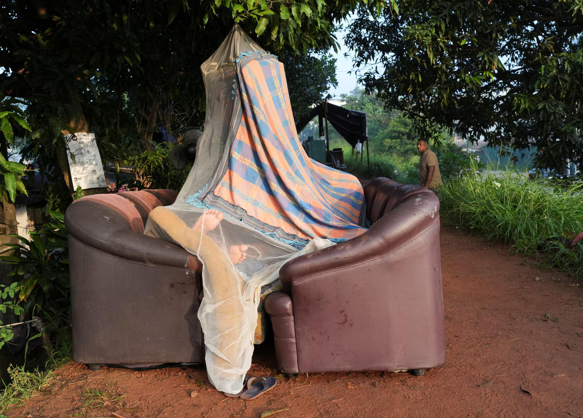 A person sleeps inside a makeshift tent made by a mosquito net and sofas along the banks of Kelani River, following Cyclone Ditwah in Peliyagoda, Sri Lanka. REUTERS/Thilina Kaluthotage