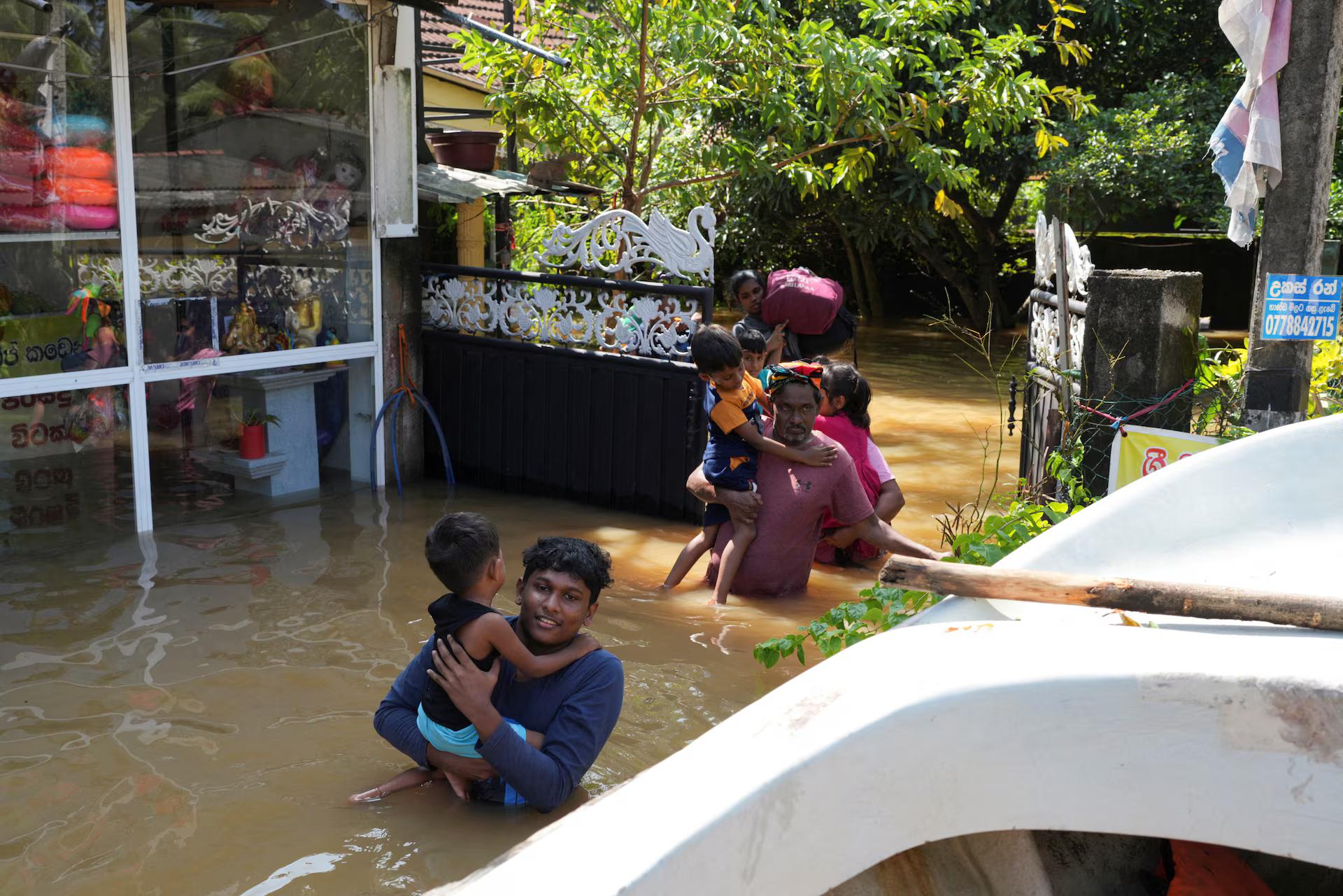 People wade through a flooded area as they head towards a boat, following Cyclone Ditwah in Kelaniya, Sri Lanka. REUTERS/Thilina Kaluthotage
