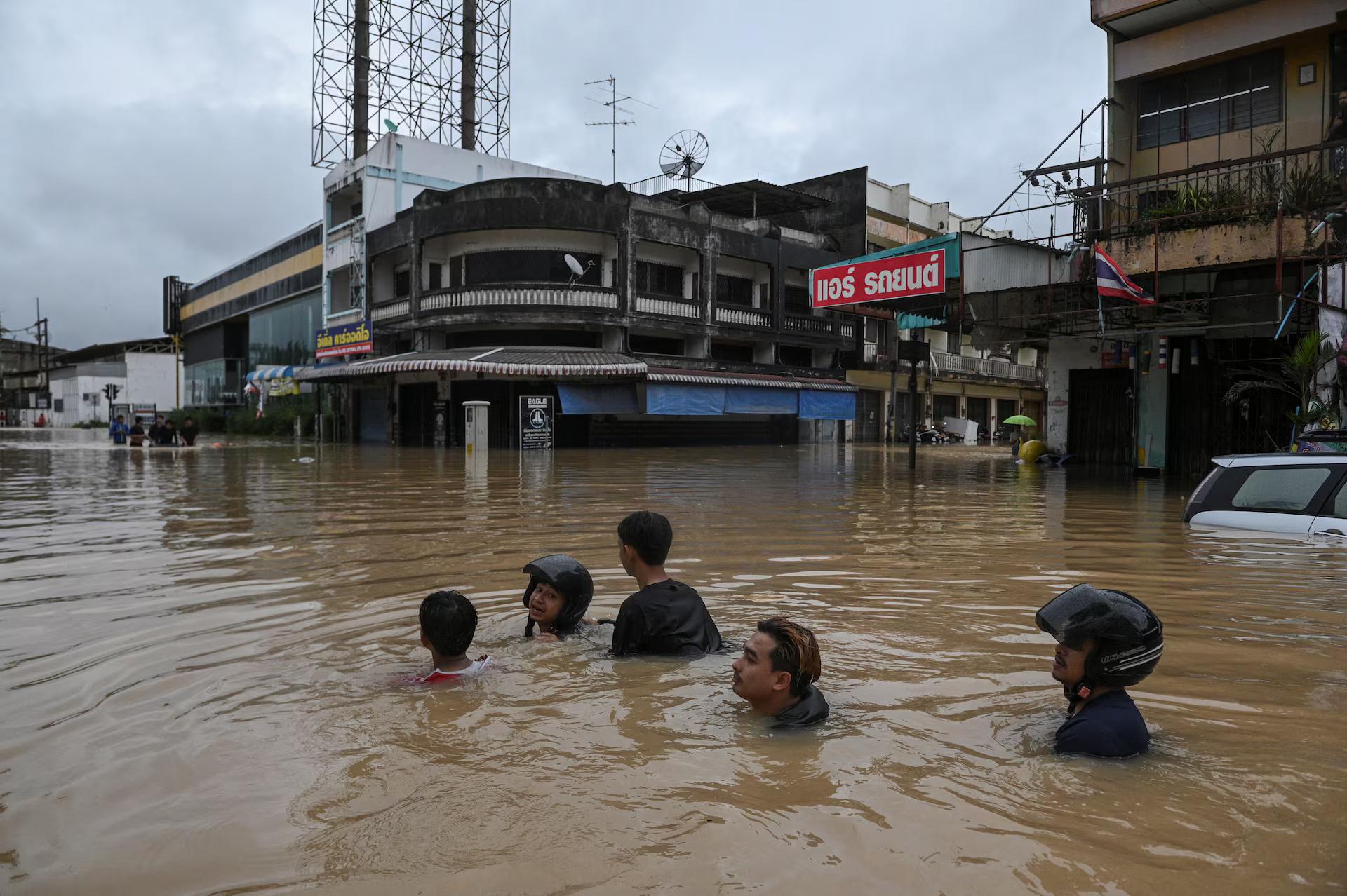 Local residents wade through an area flooded neck-deep.