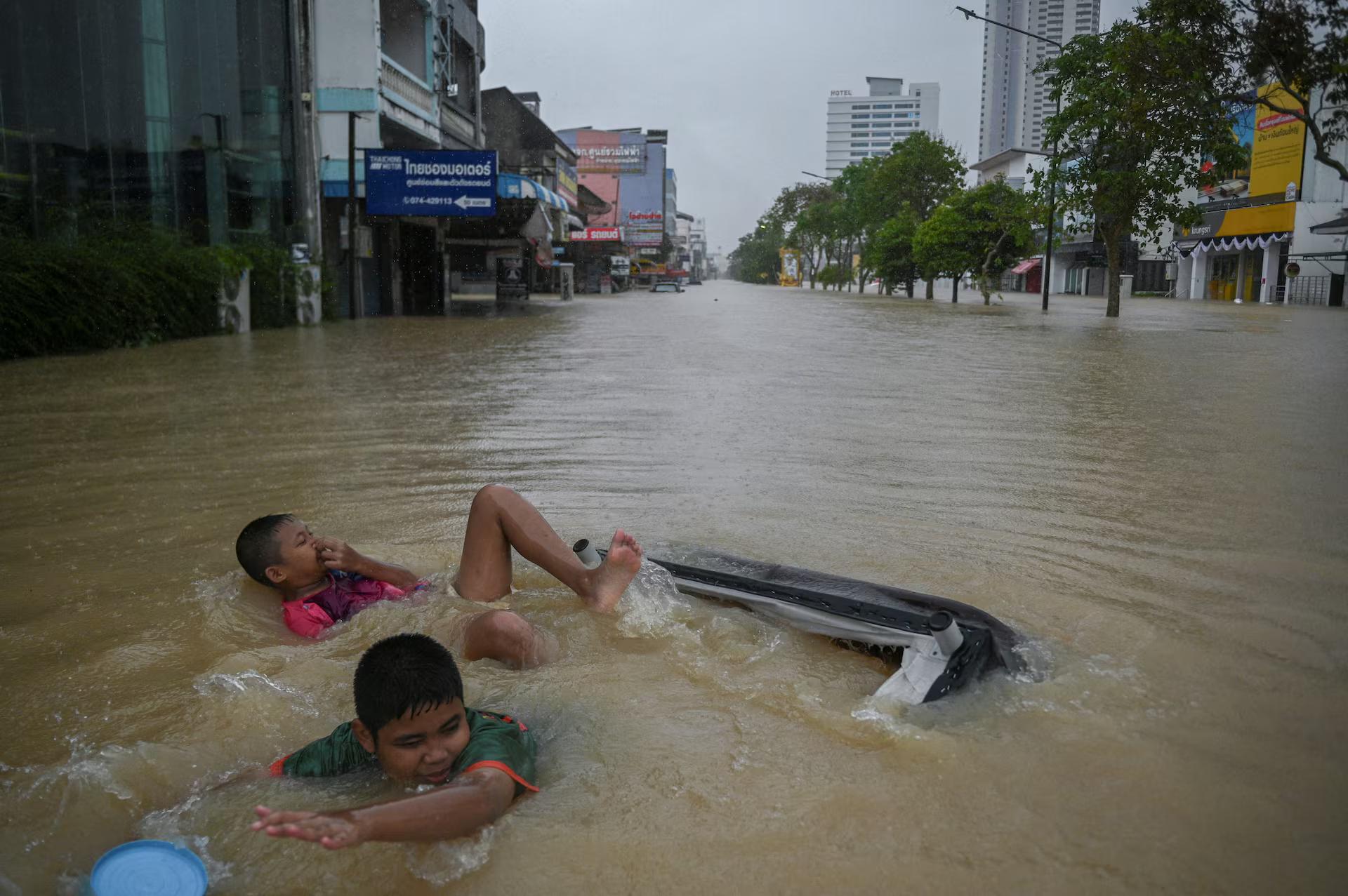 Boys swim on a flooded street.