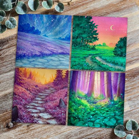  A photo of four square postcards, placed on a wooden desk and surrounded by leaves for decoration. The postcards feature traditional paintings of dreamy landscapes in vibrant colours.