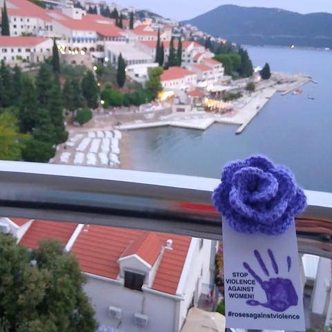 a purple crocheted purple rose in Neum, Bosnia. In background a beach and hotels