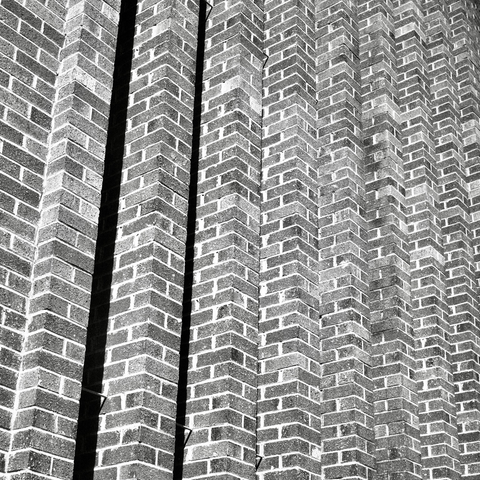 A black-and-white film photo. A dizzying vertical pattern, made by bricks, is seen on the side of a building in downtown Austin, Texas. Monday, February 19, 2024.