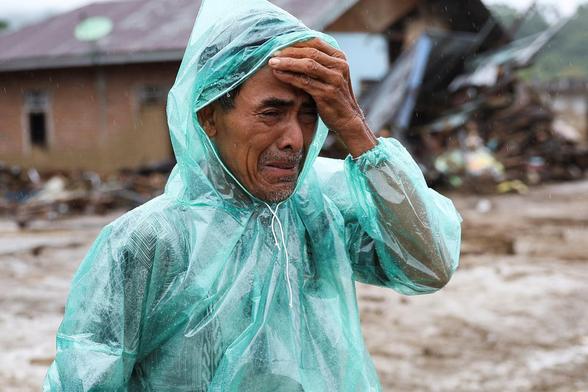 A local resident Abdul Ghani, 57, cries while looking for his wife Marsoni, who has been missing following deadly flash flood.
