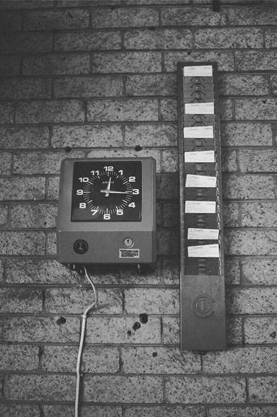 A time clock with timecards on a wall.