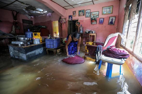 A woman tries to save her belongings inside her flood-hit home.
