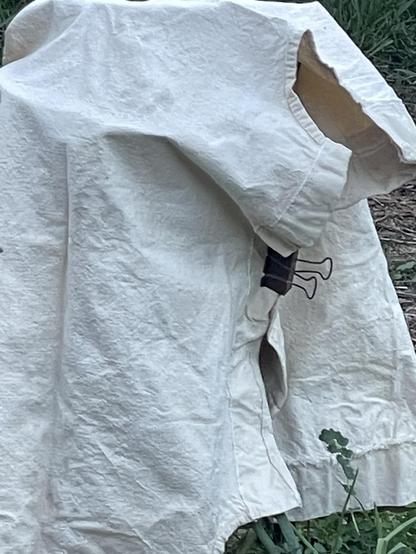 A canvas cloth from a folding cot is wrapped over and around a tomato cage and closed with binder clips