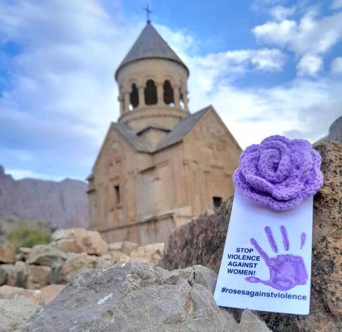 a purple crocheted purple rose in front of a church in Armenia