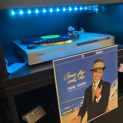 The album cover is in front of a turntable playing the album. 