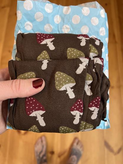 A dark brown folded tight with red and green mushrooms. The heads of the shrooms have white dots and the stems are white