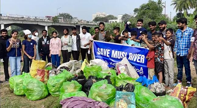 Activists of the save Musi river campaign standing around 20 or so bags full of waste after their cleanup activity.