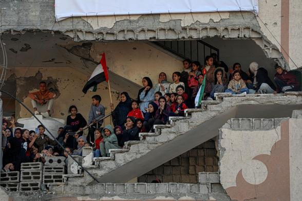 People watch a Palestinian mass wedding from the steps of a ruined building. 