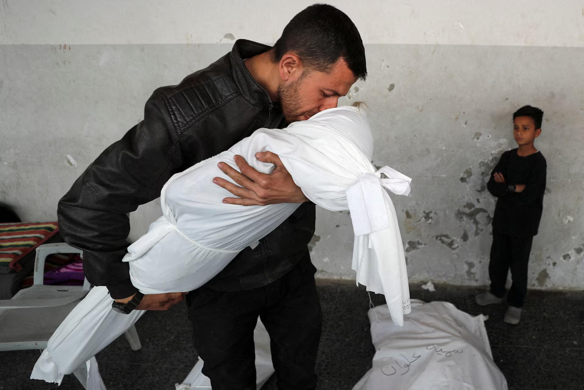 A Palestinian man kisses the body of his nephew Nour Nabhan, 5, who was killed in an Israeli strike.