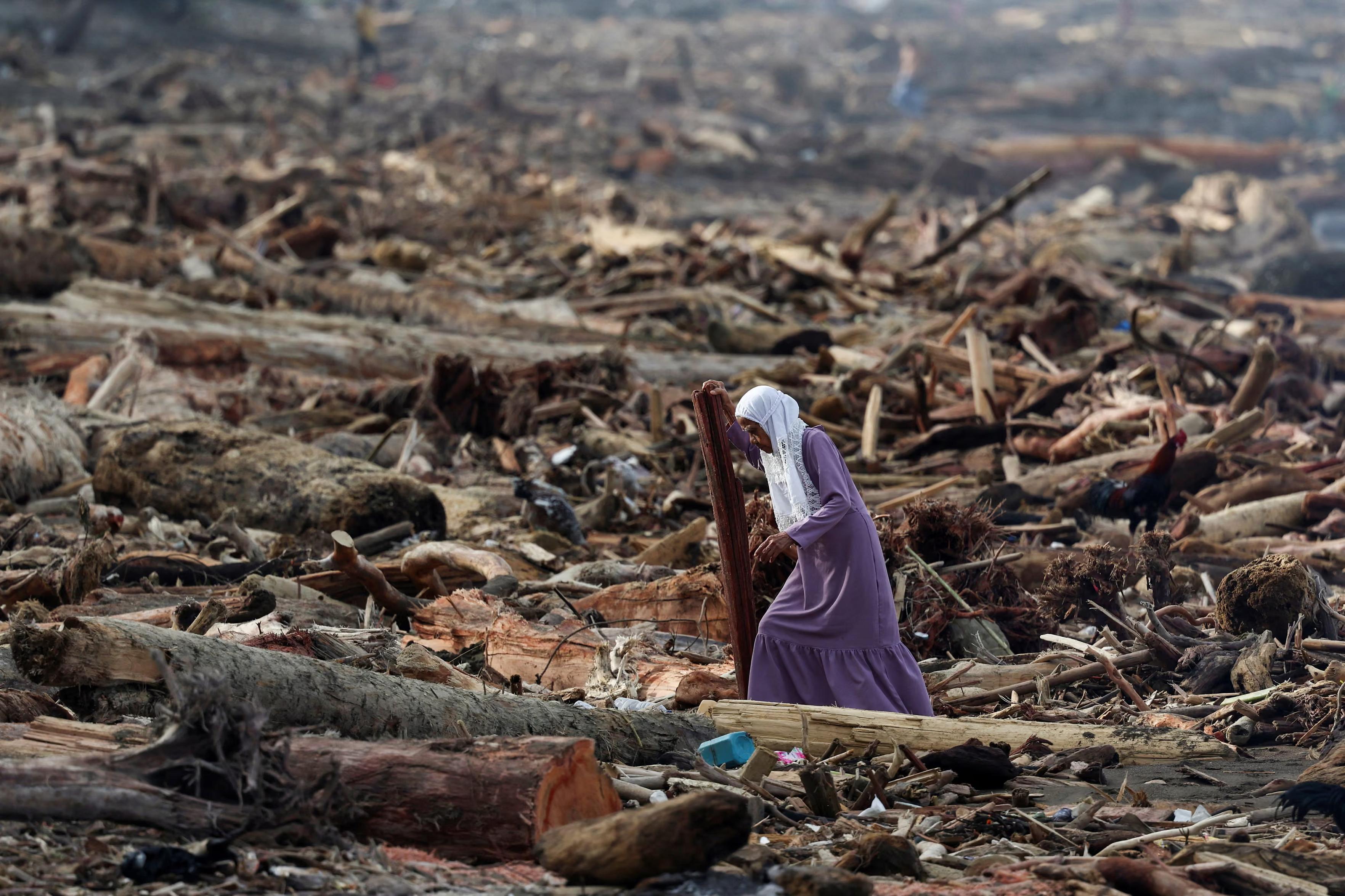 A woman walks among tree trunks following deadly flash floods and landslides.