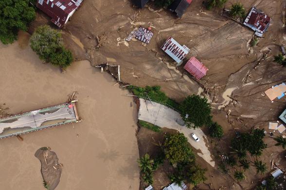 A bridge destroyed by flooding in a village in Meureudu and a surrounding area covered by mud.