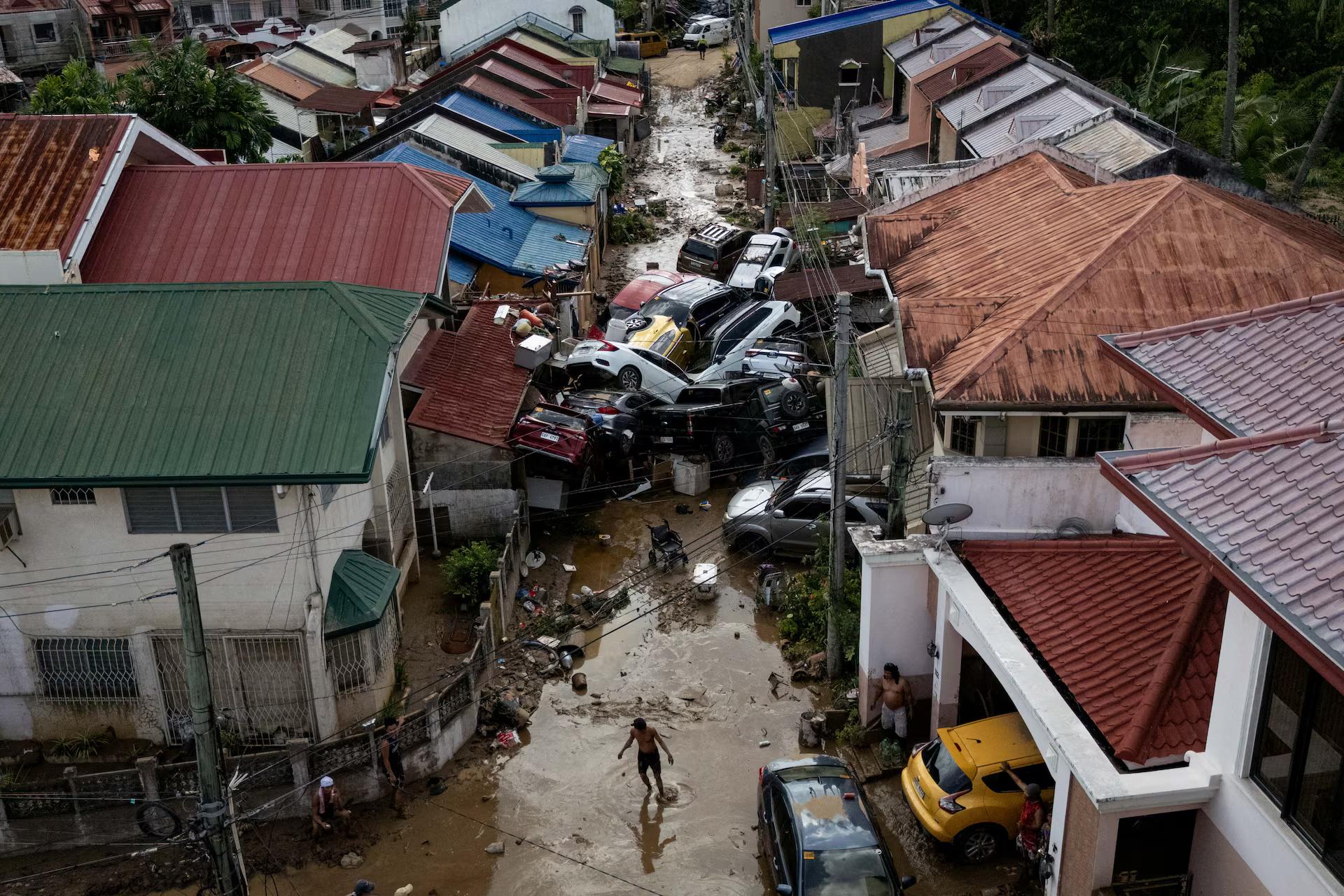 A drone view shows a man crossing a muddy street where cars piled up after being swept away in floods brought on by Typhoon Kalmaegi in Bacayan, Cebu City,