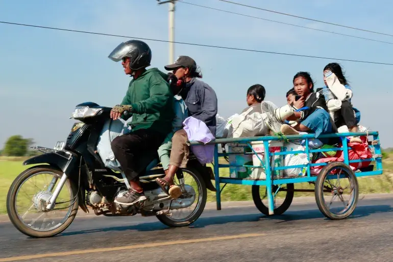 Family flees in a trailer pulled by a bike.