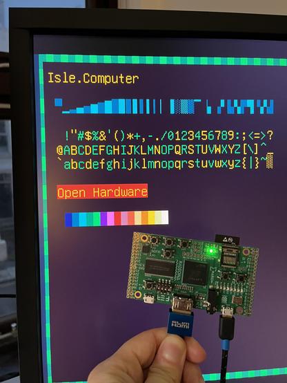 ULX3S FPGA dev board connected to widescreen monitor showing test text 16 colours. 