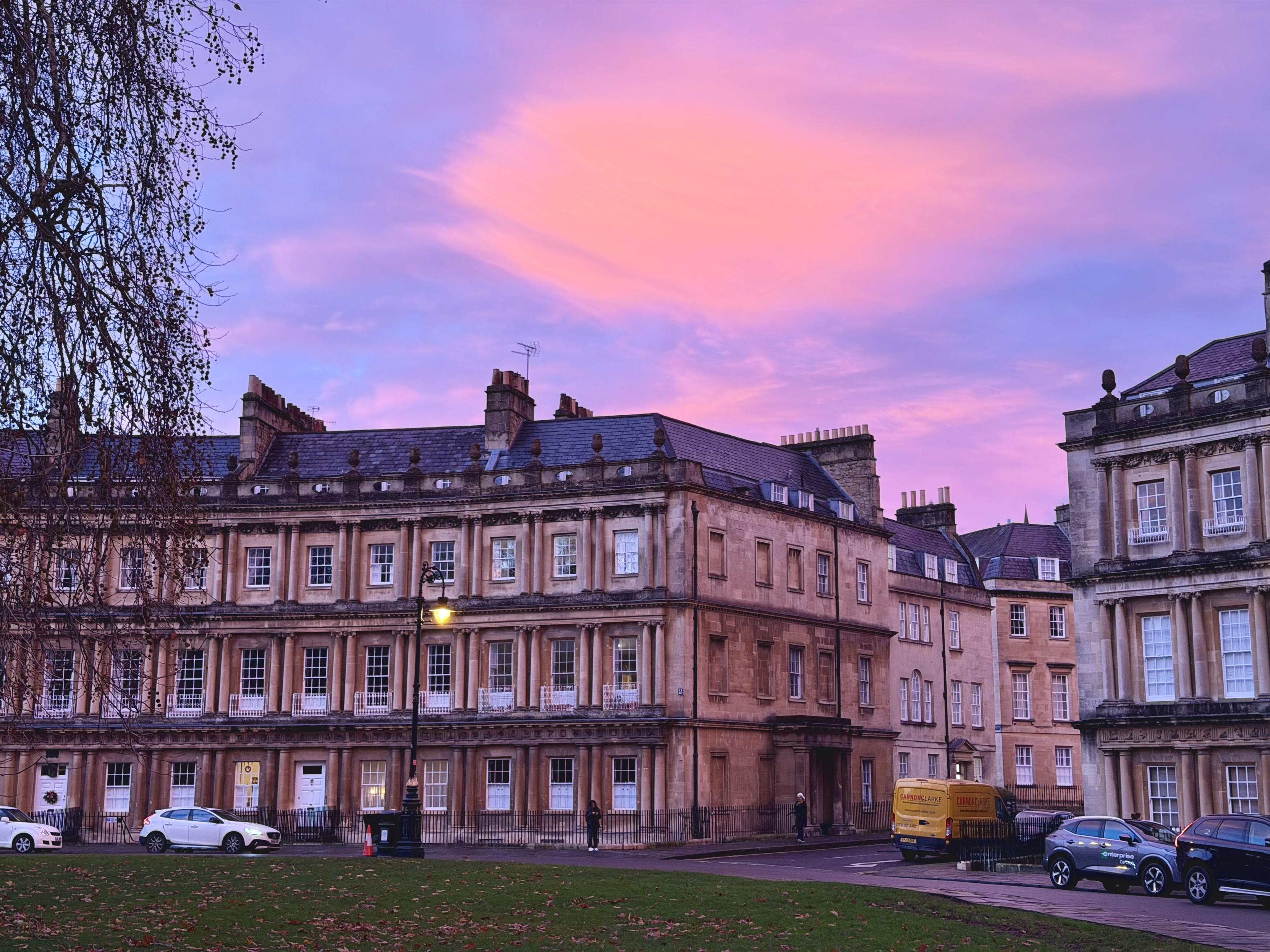A group of Georgian houses, with bright pink clouds above.