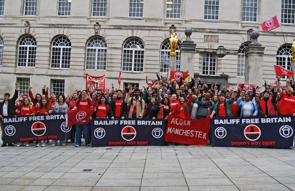 ACORN Manchester members hold 
BAILIFF FREE BRITAIN banners 