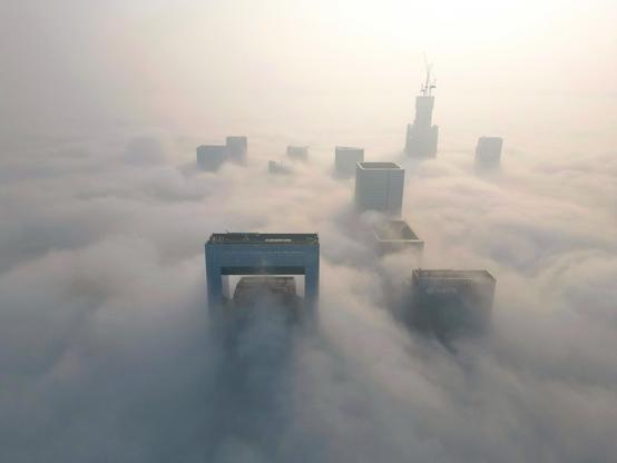 Advection fog blankets skyscrapers in the city.