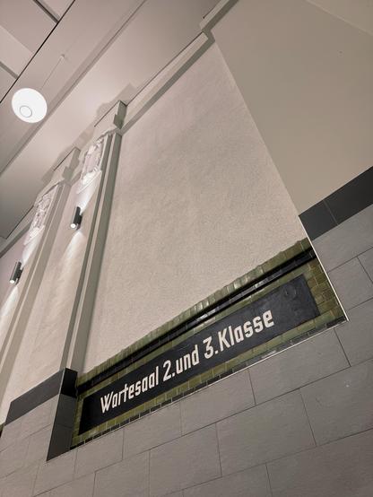 Schild „Wartesaal 2. und 3. Klasse” in historischer Bahnhofsarchitektur mit beigfarbenenen Wandfliesen