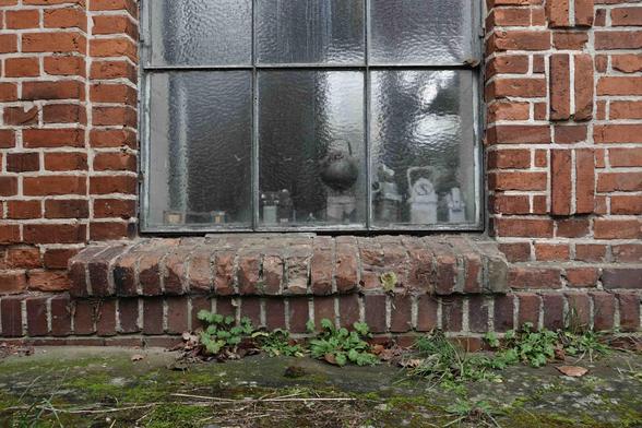 Fenster mit Metallrahmen und Sprossen in einer Ziegelwand. Digitale Farbaufnahme.