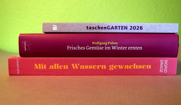 Foto eines kleinen Bücherstapels. Auf den Buchrücken steht (von oben nach unten) "Taschengarten 2026", "Frisches Gemüse im Winter ernten" und "Mit allen Wassern gewachsen".