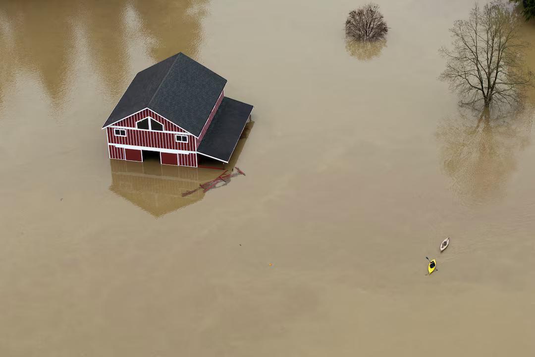 A drone view shows a kayaker paddling on floodwaters from the Snohomish River near a flooded barn, as an atmospheric river brings rain and flooding to the Pacific Northwest, in Snohomish, Washington, December 11, 2025. REUTERS/David Ryder