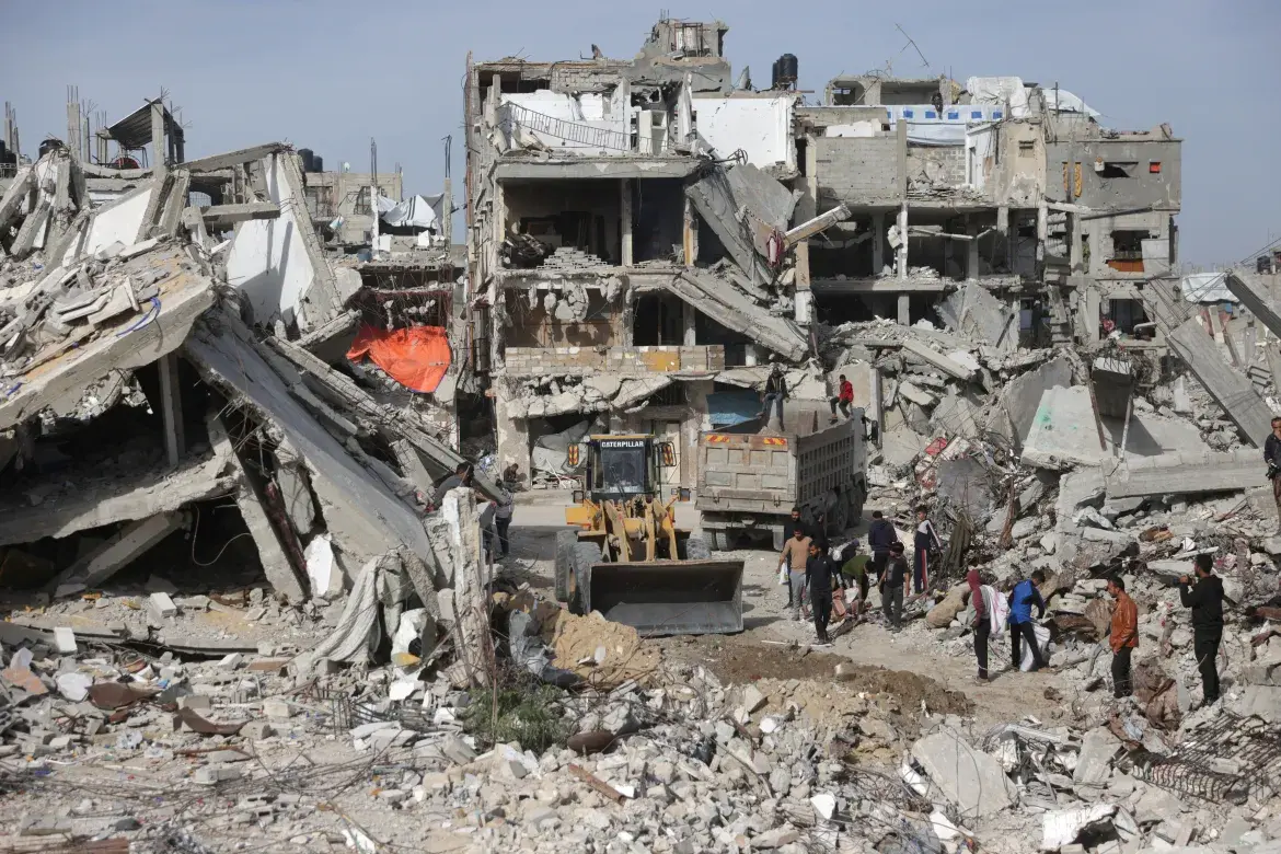A Palestinian worker operates a digger to move concrete, metal, and debris from destroyed buildings and houses in Khan Younis.
